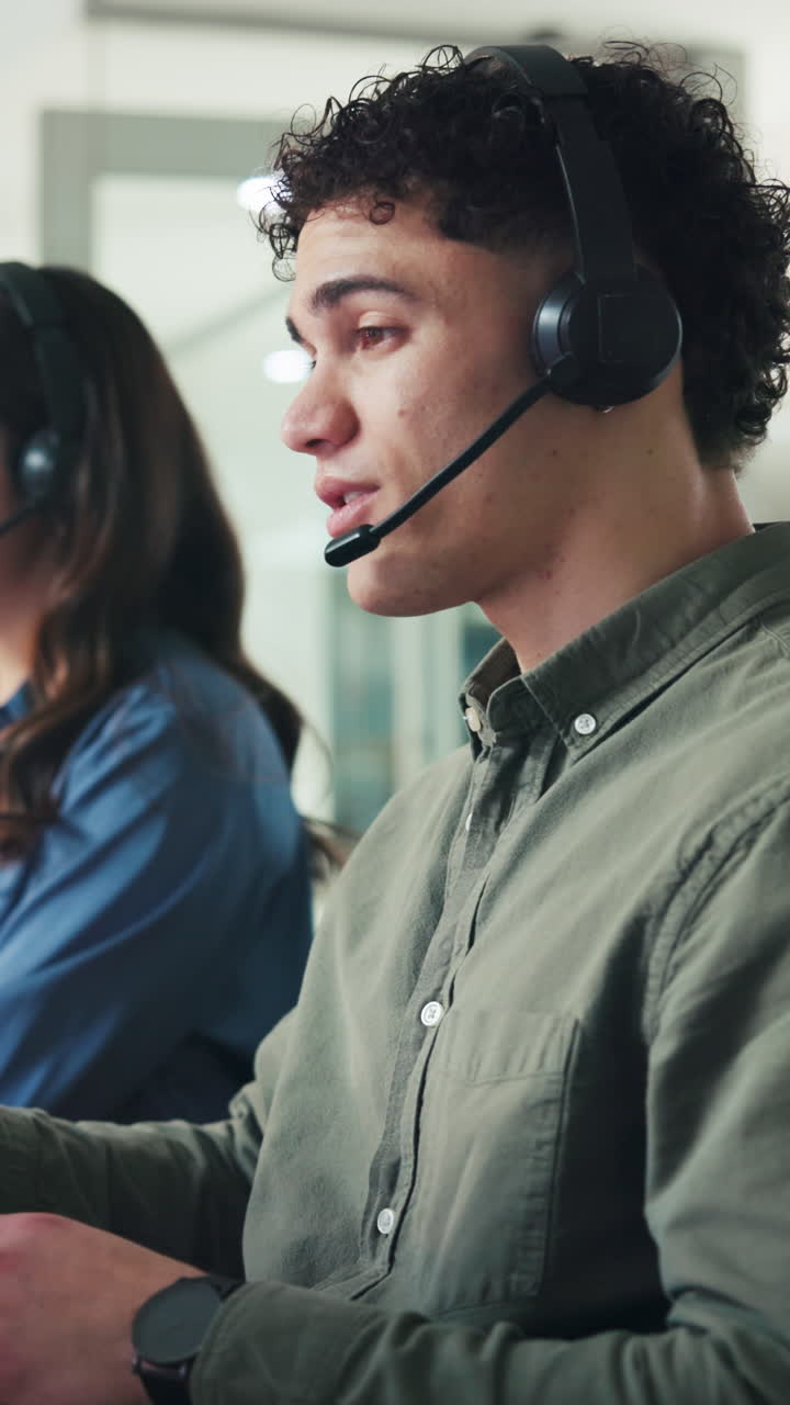 Young Man Wearing Headset Speaking in Call Center Office