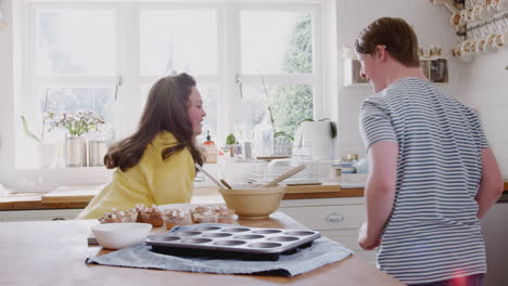 una pareja joven con síndrome de down decora pasteles caseros y baila en la cocina de su casa.