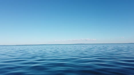 matching hues of blue sky and ocean fill the frame offshore from brisbane, queensland, with the faint outline of land in the background.