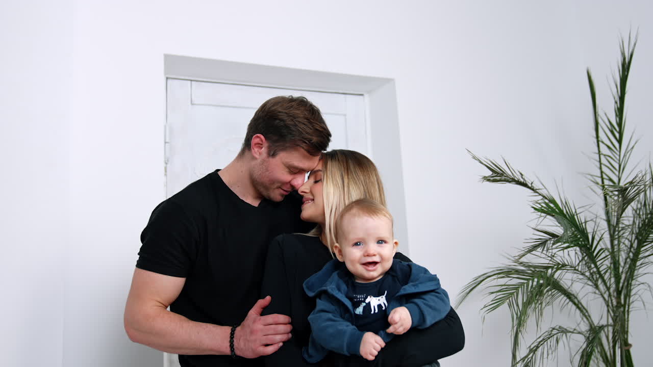 Happy Caucasian couple with their smiling baby in hands. Beautiful family portrait of three.