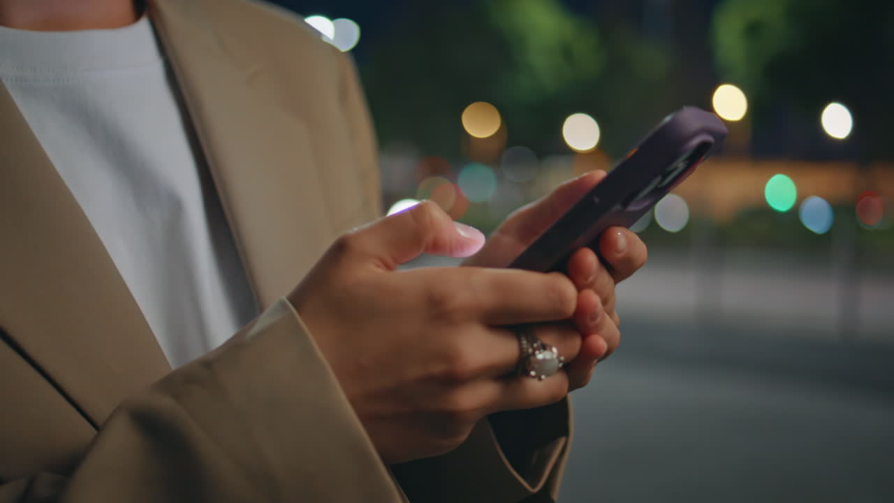 Mani di donna d'affari digitano sullo smartphone in una strada buia, primo piano. Donna sconosciuta.