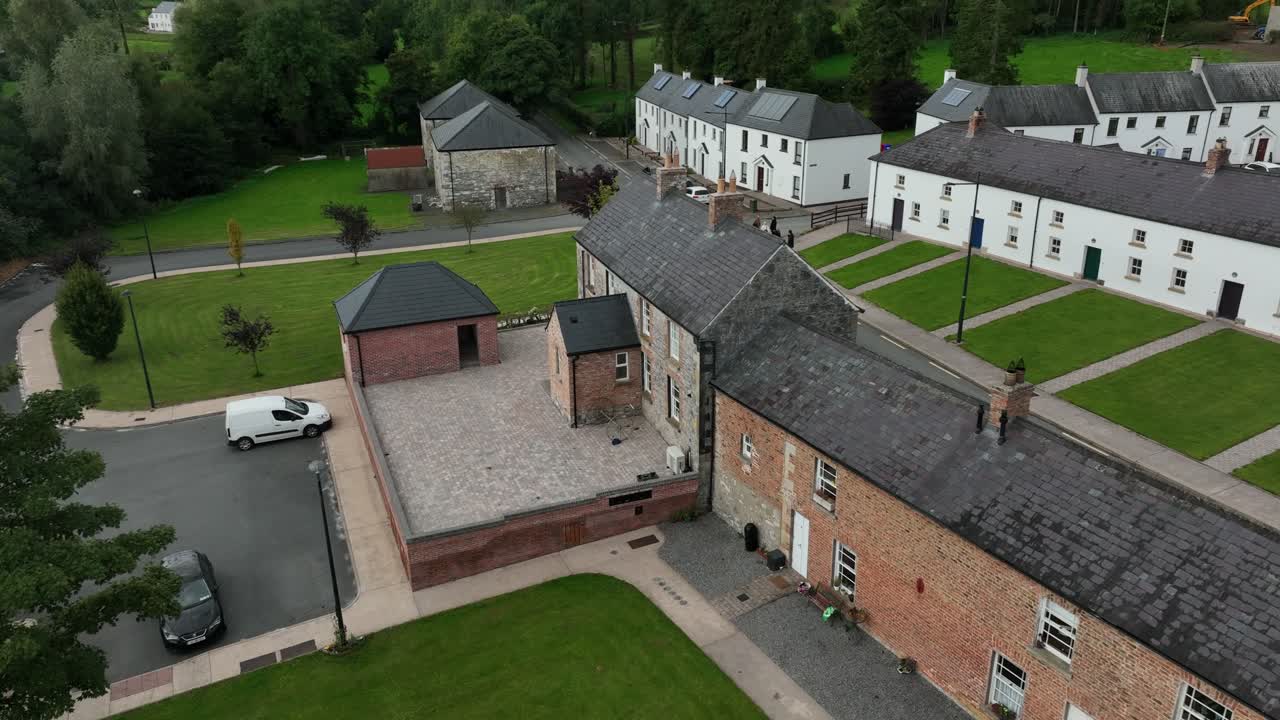 Mullan Village, County Monaghan, Ireland, September 2022. Drone orbits clockwise above the slate roofs chimneys and tidy lawns in front of a heritage houses close to the border with Northern Ireland.