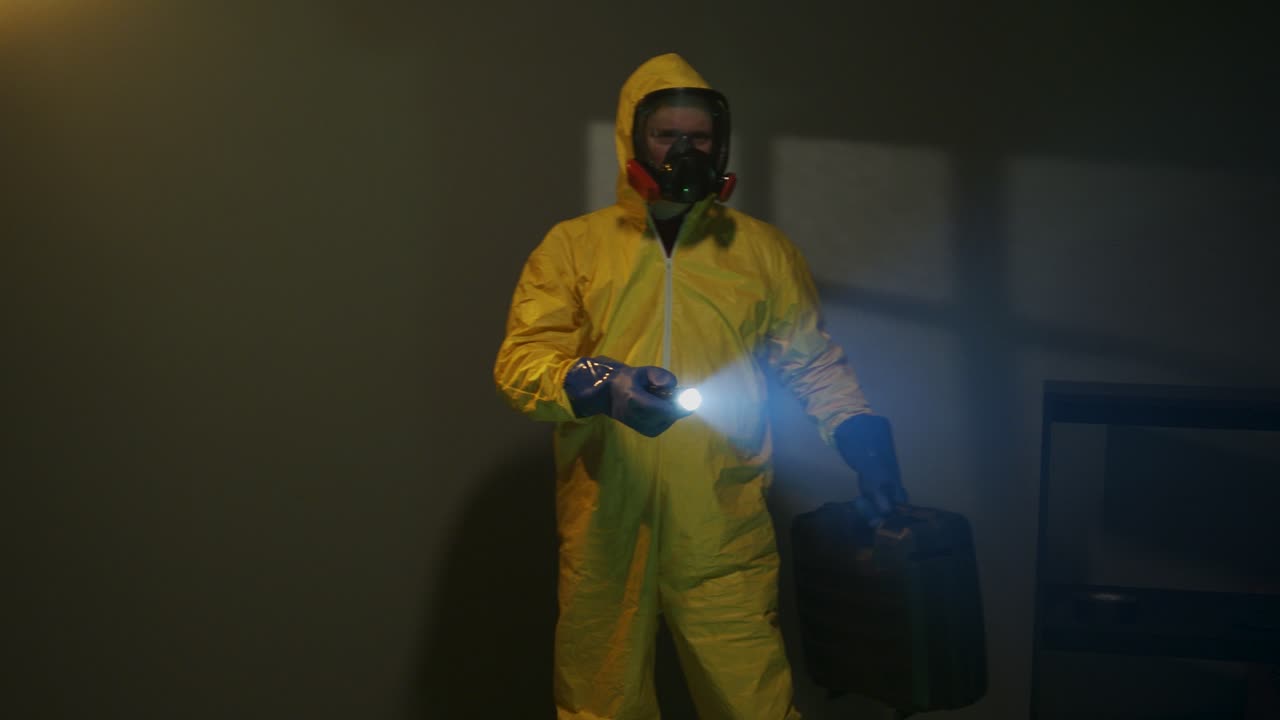 Mann i hazmat-drakt utforsker et mørkt rom