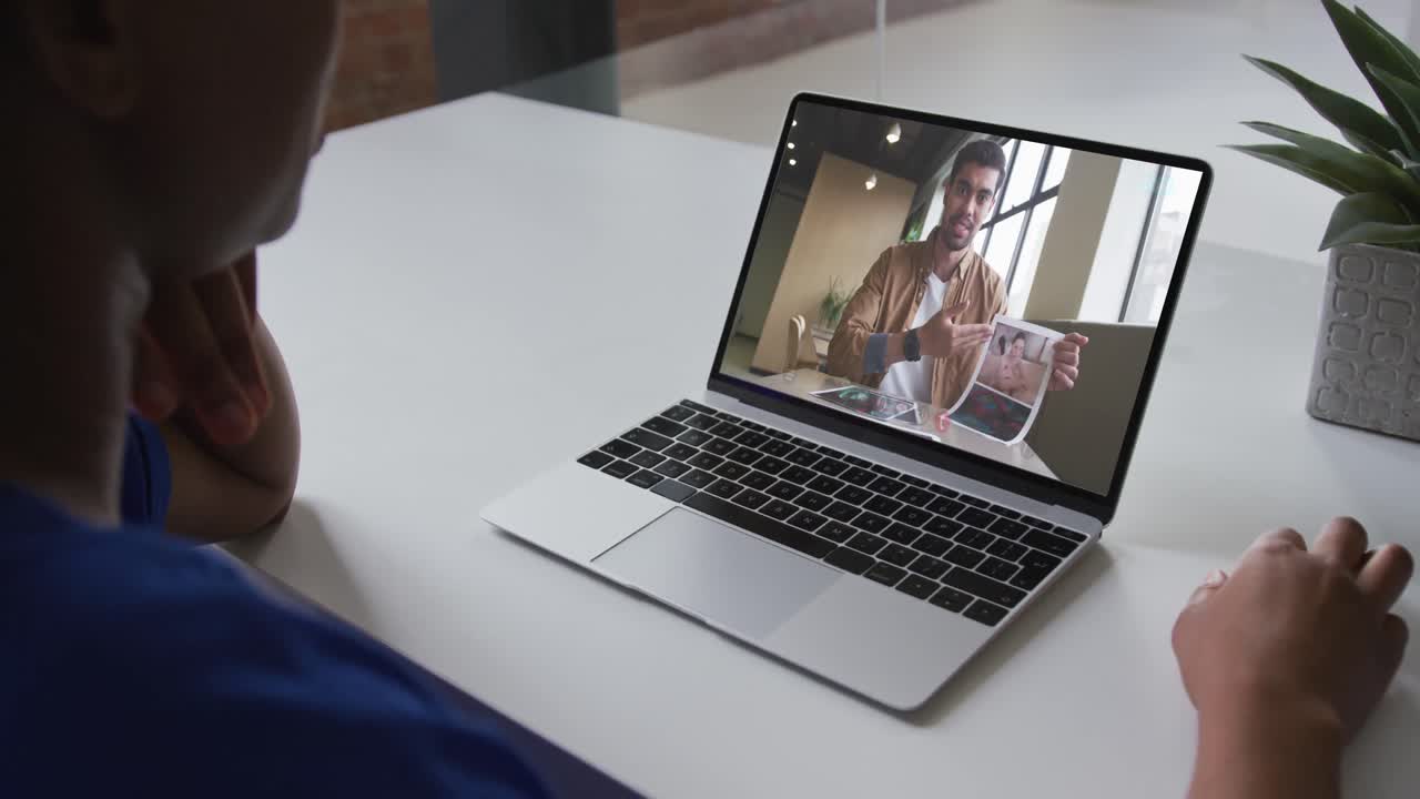 Mid section of african american woman having a video call with male colleague on laptop at office