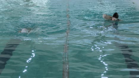 two people swimming laps in an indoor pool