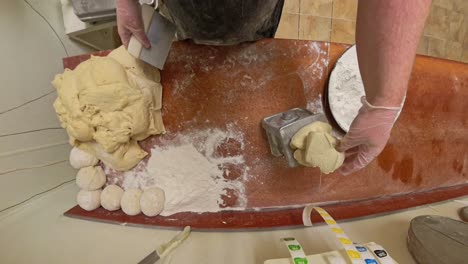top down of worker cutting and weighing raw dough.