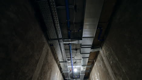 light and ventilation communications on the ceiling of the long corridor. low angle view. construction site interior.