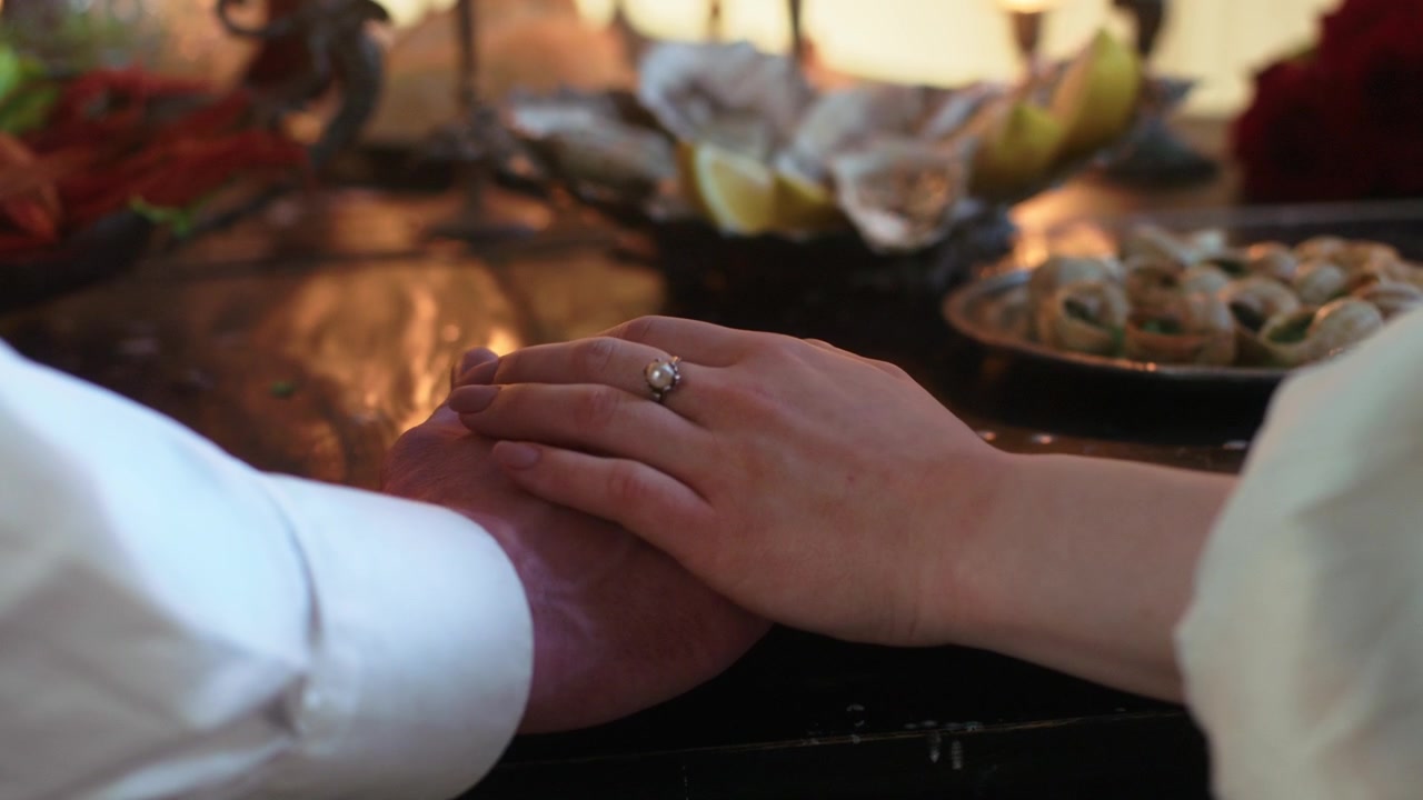 Close-up of Couple's Hands with Engagement Ring at Dinner