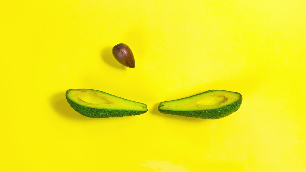 Un avocado è diviso a metà. Le due metà si lanciano il nocciolo a vicenda, come se stessero giocando a tennis