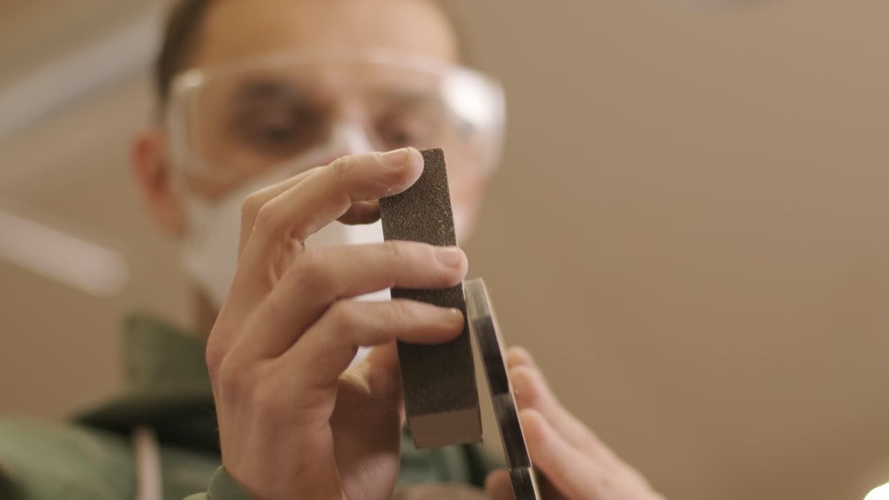 un carpintero está moliendo una pieza de madera, un producto de madera contrachapada hecho en una máquina láser cnc usando papel de arena