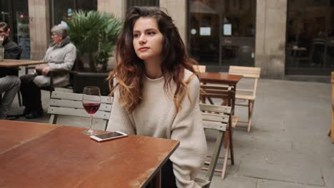 young girl thoughfully looking something sitting in outdoor cafe