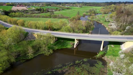 drone slow dolly shot forward old bridge in łęczna, poland with cars, river, and green nature