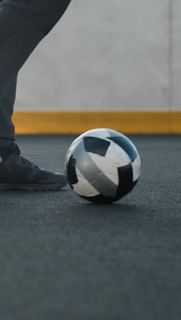 vista lateral de la pierna de un atleta que muestra giros precisos del tobillo con la pierna izquierda y derecha, maniobrando hábilmente una pelota de fútbol en una arena deportiva con una pared pintada