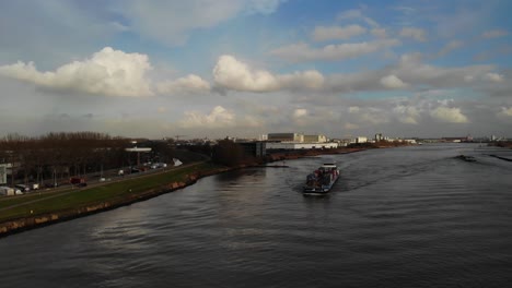 Fully-loaded-cargo-barge-sailing-on-the-dutch-river-oude-maas-towards-the-next-destination-carrying-containers-in-the-hold-on-a-partly-cloudy-day