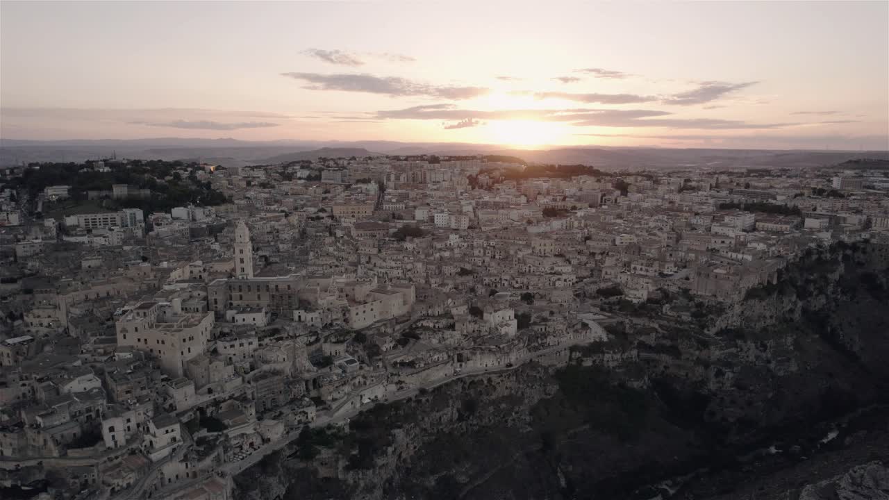 drone volando de lado y un poco hacia adelante filmando la antigua ciudad blanca de matera al atardecer en el sur de italia en 4k