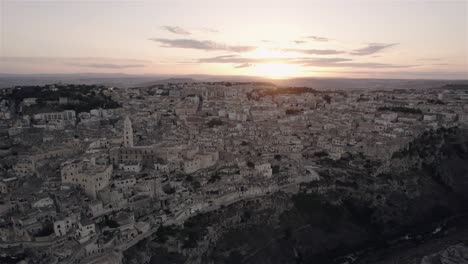 Drone-Volando-De-Lado-Y-Un-Poco-Hacia-Adelante-Filmando-La-Antigua-Ciudad-Blanca-De-Matera-Al-Atardecer-En-El-Sur-De-Italia-En-4k