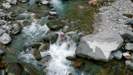 tilting drone shot over the flowing waters of river maggia, situated in the village of cavergno, vallemagia district, canton of ticino, in switzerland