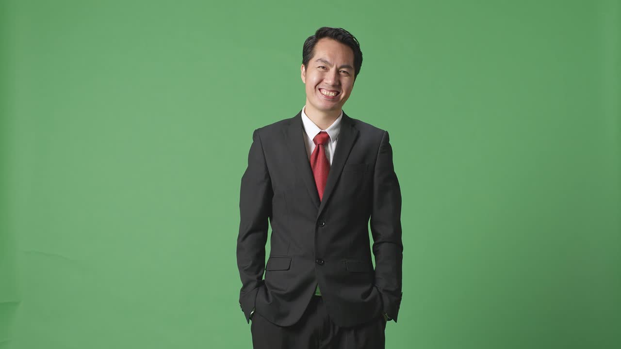 스튜디오의 녹색 스크린 배경에서 따뜻하게 미소 짓는 아시아 사업가