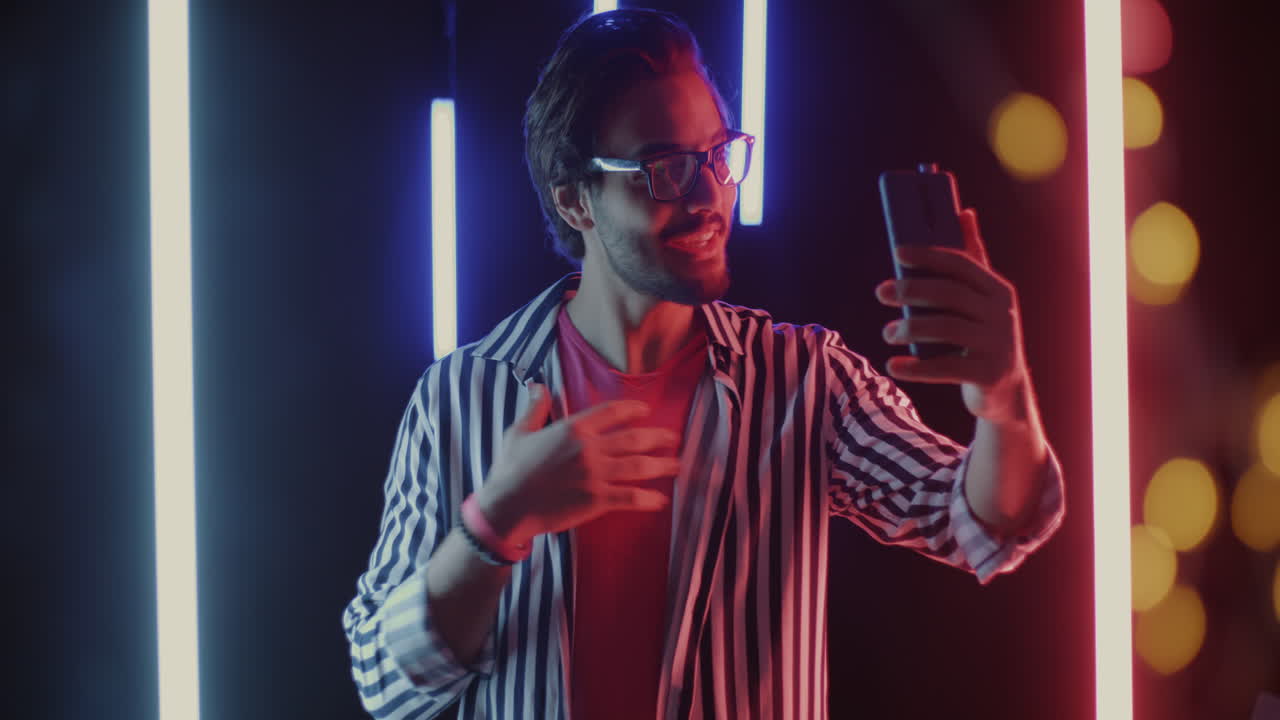 Man taking a selfie or video call in a neon-lit environment
