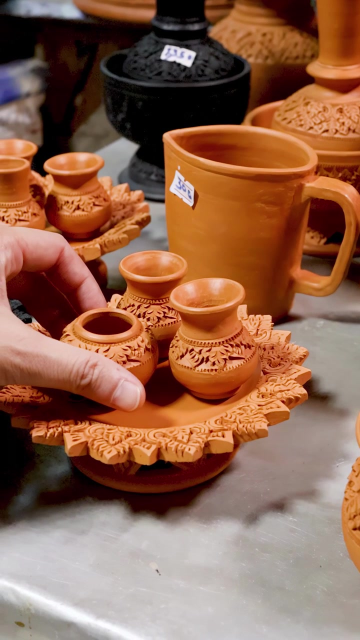 Mano ajustando cerámica de arcilla tailandesa tradicional en exhibición.