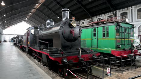 a view inside the historic madrid railway museum (museo del ferrocarril), showcasing a collection of preserved locomotives and vintage train cars from spain's rich railway heritage.