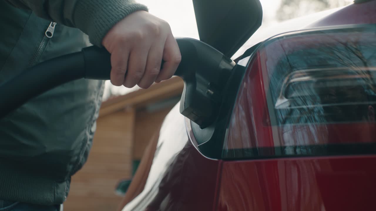 Man opens the charging port flap to charge the electric car