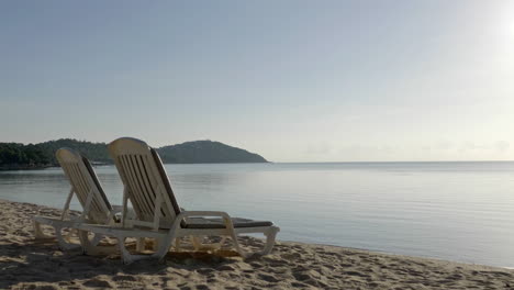 Statische-Aufnahme-Von-Liegestühlen-Am-Strand-Mit-Den-Bergen-Im-Hintergrund