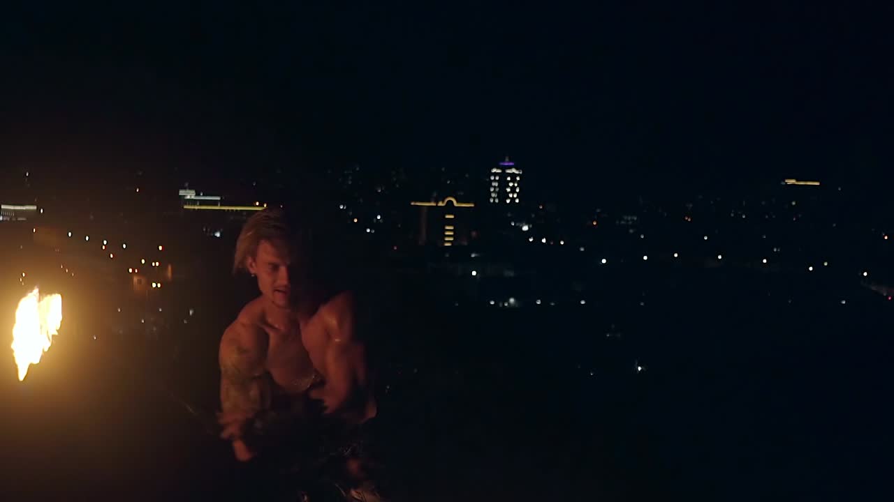 젊은 금발 남자가 두 마리의 불타는 독을 회전시켜 느린 동작으로 가까이