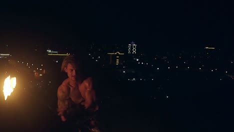 young blond male spins two burning pois slow motion close up