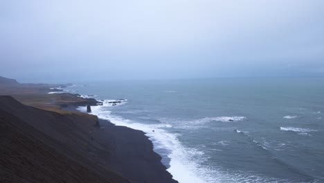 olas golpeando la costa de arena negra en islandia en un clima tormentoso