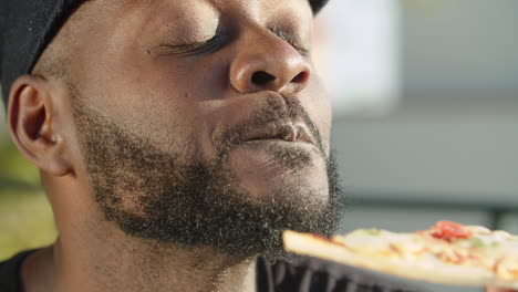 primer plano de gay afroamericano comiendo deliciosa pizza