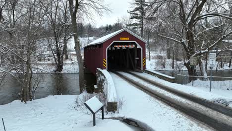 aerial establishing shot of a covered bridge over a stream