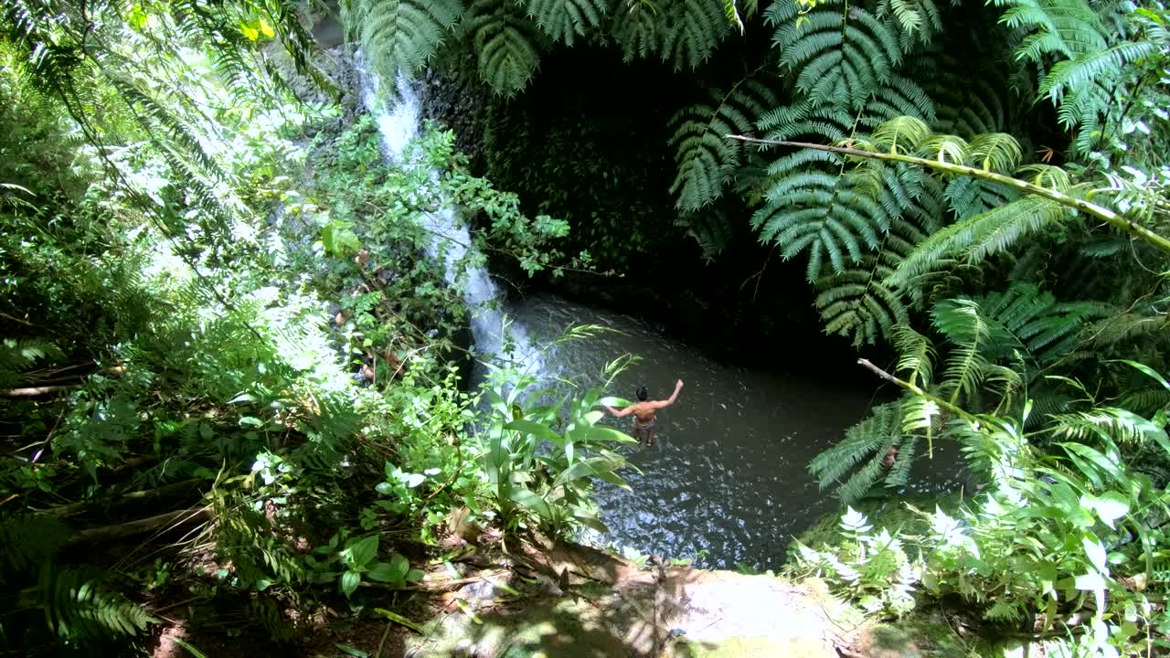 toma en cámara lenta de 4k de un hombre saltando desde un alto acantilado al agua en maunawili falls en oahu, hawaii