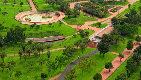 aerial orbit of a cyclist and people jogging and enjoying the outdoors at virgilio barco park in bogota, colombia. natural green environment