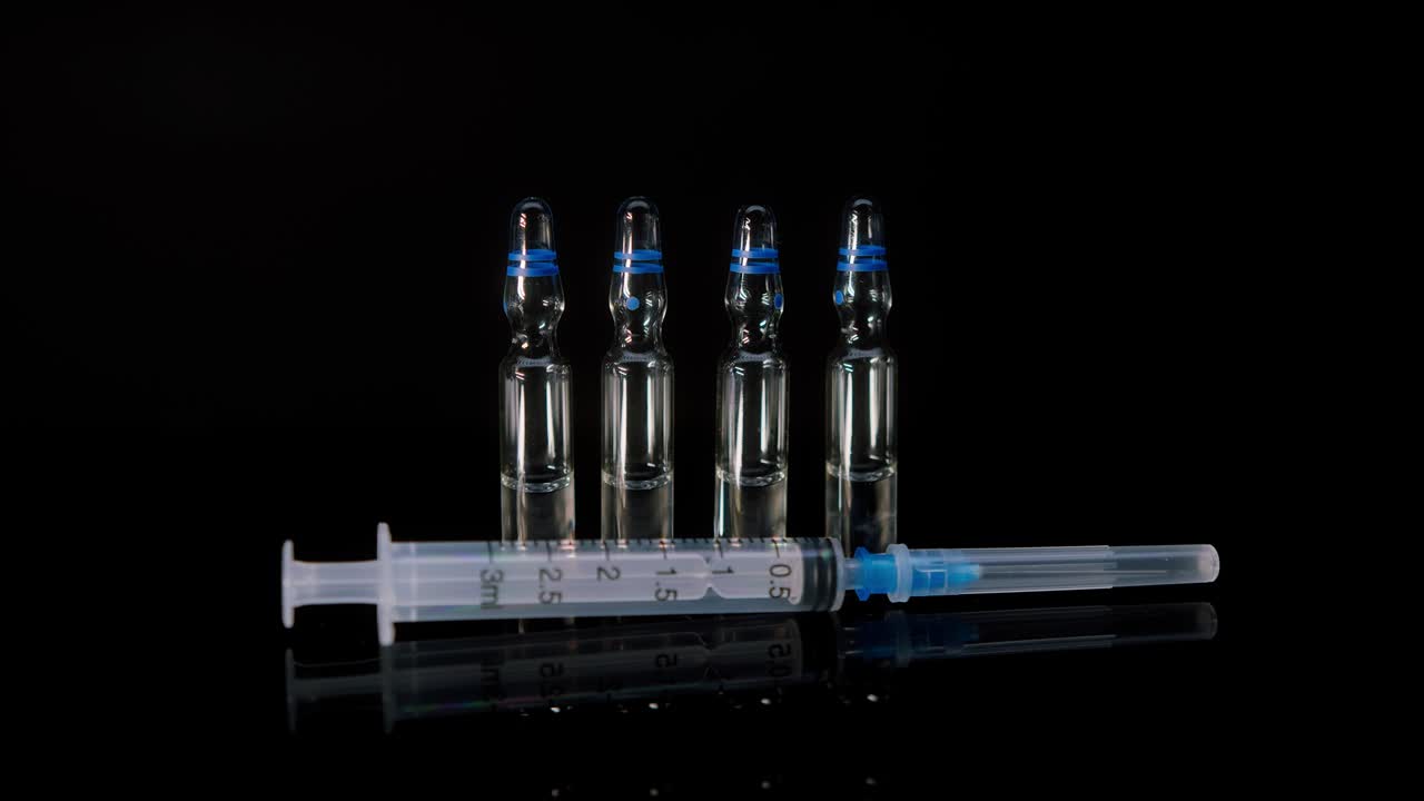 코로나바이러스 백신을 가진 주사기와 플의 클로즈업 - 검은색 배경에 의약품 플, 코로나19 백신 접종, 실험실 연구 개념