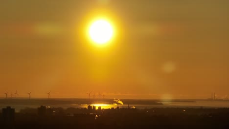 primer plano de una puesta de sol con molinos de viento en el fondo, antena