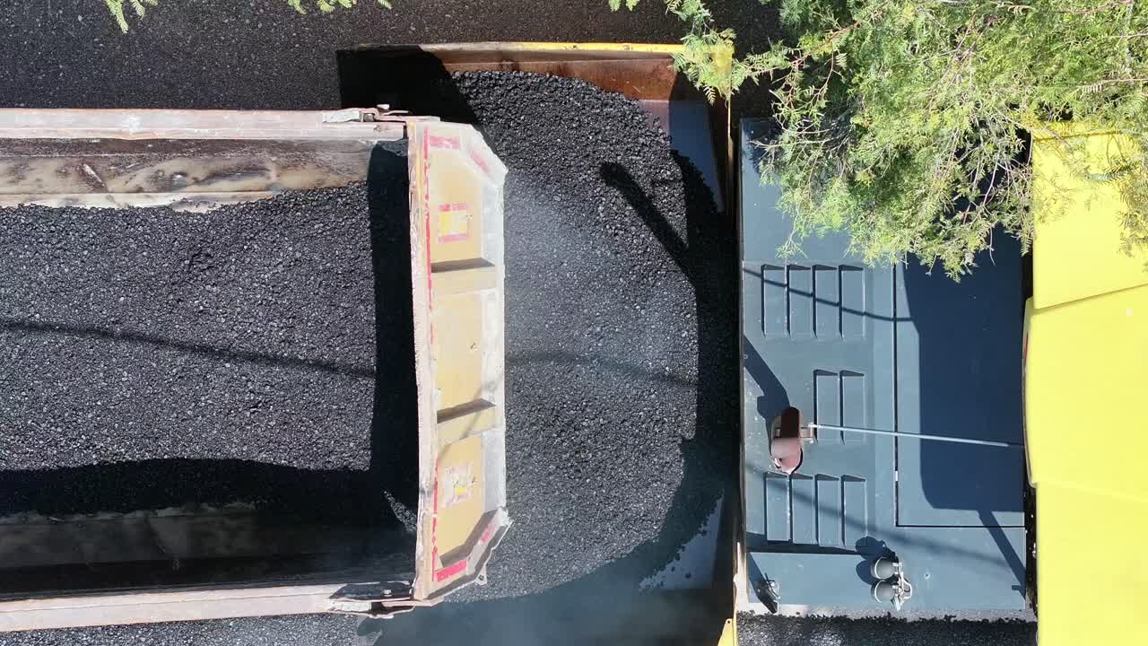 Aerial shot 4k footage while truck pouring asphalt on asphalt machine