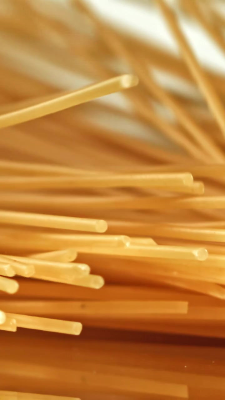 Spaghetti secchi che cadono su una superficie riflettente