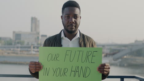 man holding a sign: our future in your hand