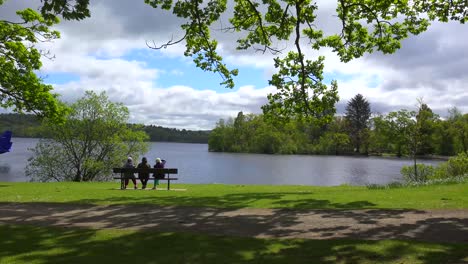 ludzie siedzą na ławce, ciesząc się scenerią w loch lomand szkocja