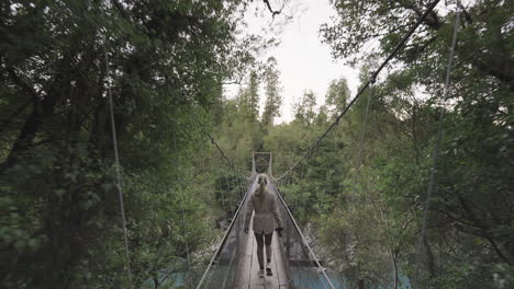 female tourist walking on suspension bridge stopping to take photo of hokitika gorge