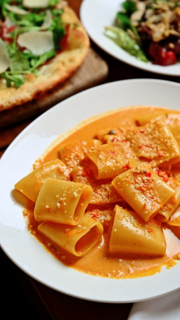 Piatto di pasta cremosa con formaggio servito su un piatto bianco in un ristorante. La pasta è ricoperta di salsa cremosa e formaggio su un piatto bianco, su un tavolo da pranzo in un ristorante