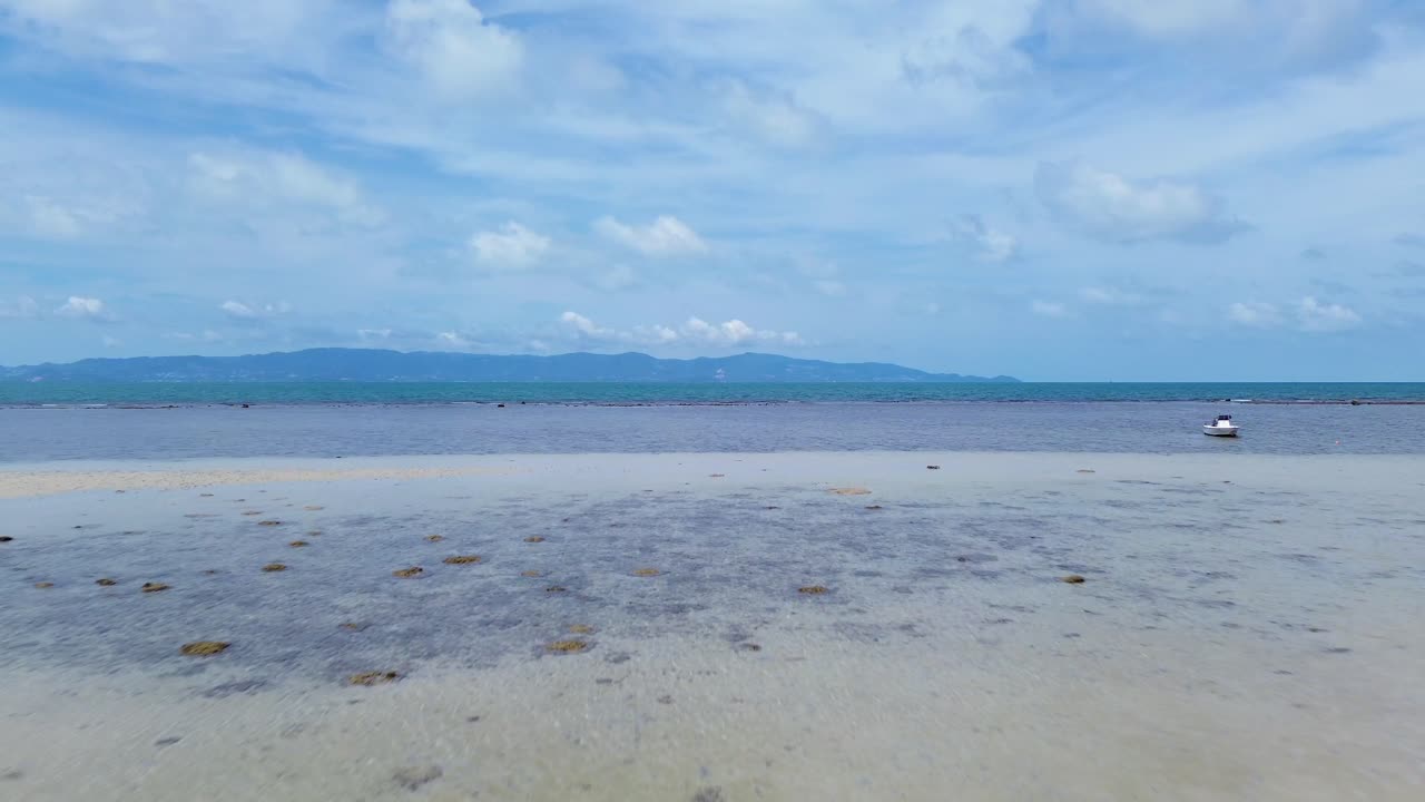 Aerial drone footage flying from Koh Phangan beach towards Koh Samui, showcasing turquoise waters, tropical islands, and scenic coastline
