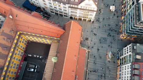 Toma-Aérea-Inclinada-Hacia-Arriba-Que-Muestra-A-Un-Peatón-Caminando-En-La-Calle-En-Munich-Al-Atardecer,-Alemania