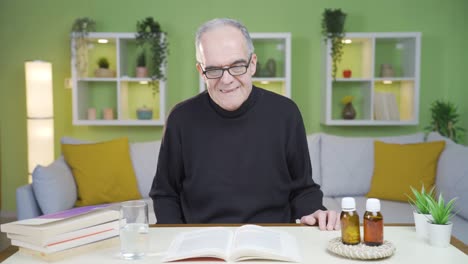 the old man gets emotional while reading a book and drinks from the water on the table.