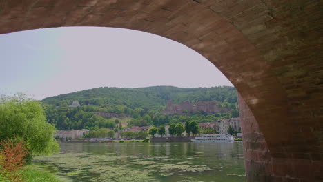 heidelberg view under karl-theodor-brücke bridge, river neckar, a tourist boat on a sunny day