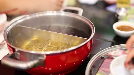 boiling hotpot with hands preparing ingredients