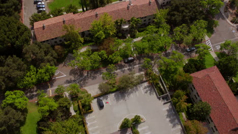 Aerial-overhead-view-of-an-empty-parking-lot-with-a-tilt-up-and-forward-over-beautiful-Occidental-College-campus-in-Eagle-Rock-in-Los-Angeles,-California