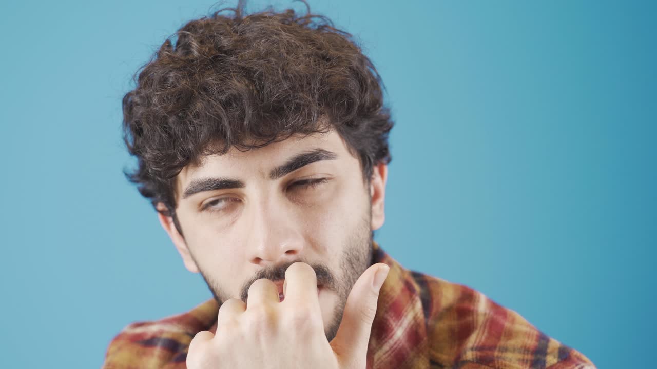 Giovane uomo stressato e preoccupato che si morde le unghie