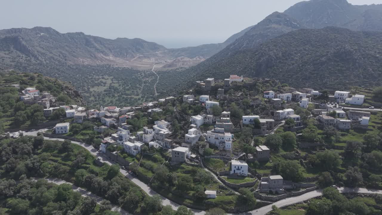 Bird's eye view revealing the beauty of Nikia village, Island Nisyros, Greece - drone footage of the settlement and volcanic caldera behind it. Filmed with 3x telephoto lens in D-Log M profile